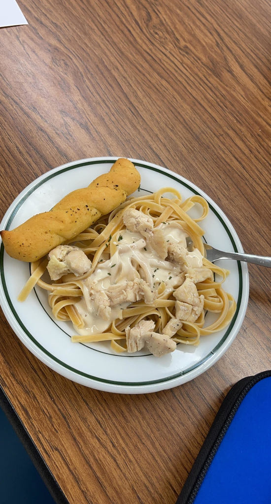 Chicken Alfredo nicely plated with a golden garlic breadstick.